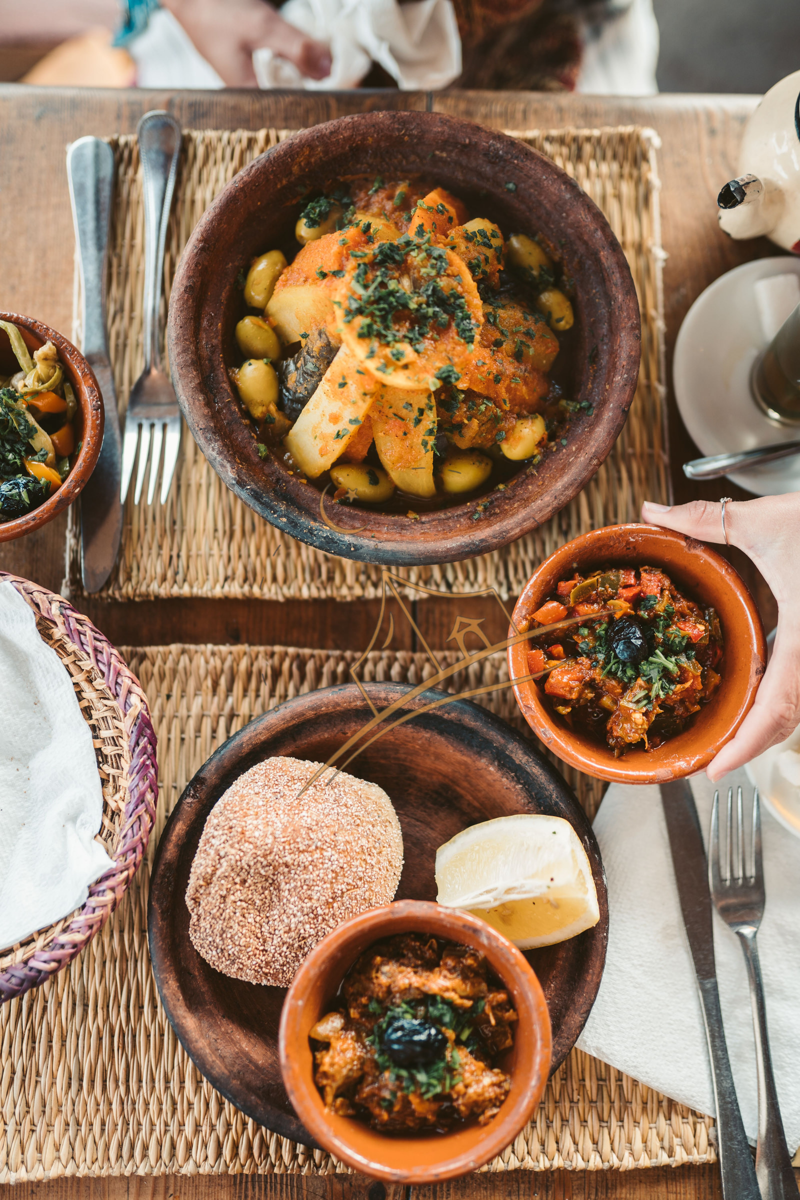 Traditional Moroccan tagines and mezze bowls shared at a rustic wooden table
